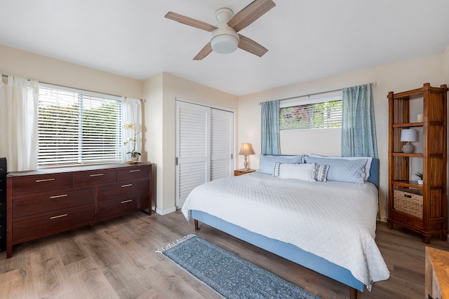 bedroom with multiple windows, ceiling fan, a closet, and light wood-type flooring