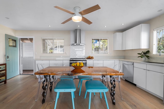 kitchen with white cabinetry, sink, stainless steel appliances, and wall chimney range hood