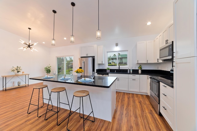 kitchen featuring white cabinets, a kitchen island, stainless steel appliances, and pendant lighting