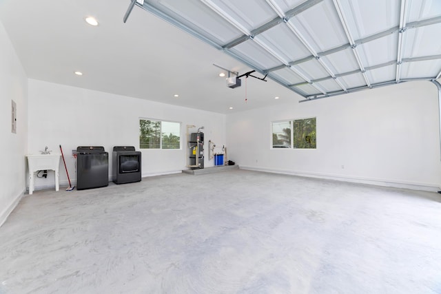 garage featuring separate washer and dryer, water heater, sink, and a garage door opener