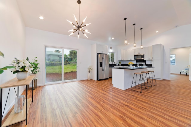 kitchen with decorative light fixtures, white cabinetry, appliances with stainless steel finishes, and light hardwood / wood-style flooring