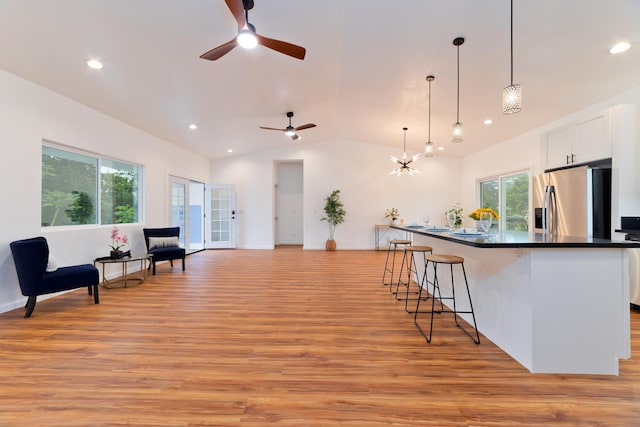 living area with light hardwood / wood-style flooring, ceiling fan with notable chandelier, and lofted ceiling