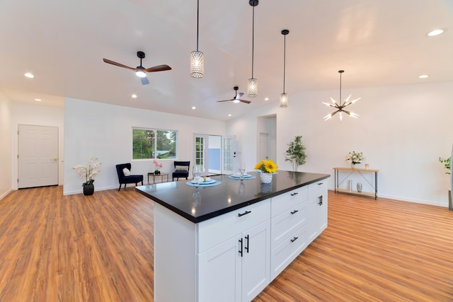 kitchen with white cabinets, light hardwood / wood-style floors, vaulted ceiling, and a kitchen island