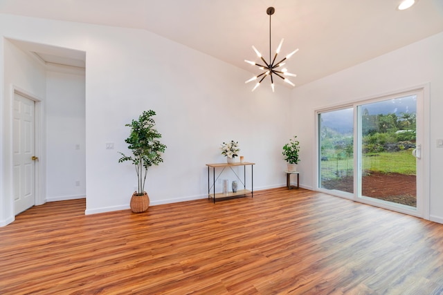 spare room featuring light hardwood / wood-style floors, vaulted ceiling, and a chandelier