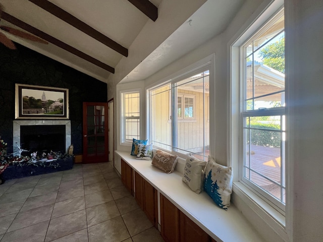 living area with lofted ceiling with beams, a high end fireplace, light tile patterned flooring, and plenty of natural light