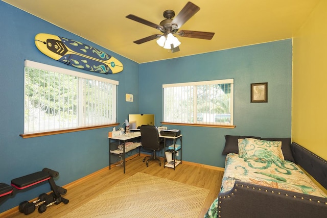 bedroom featuring hardwood / wood-style flooring, ceiling fan, and multiple windows