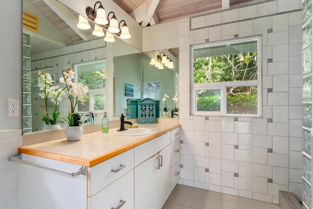 bathroom featuring vanity, lofted ceiling with beams, an inviting chandelier, tile walls, and tile patterned flooring