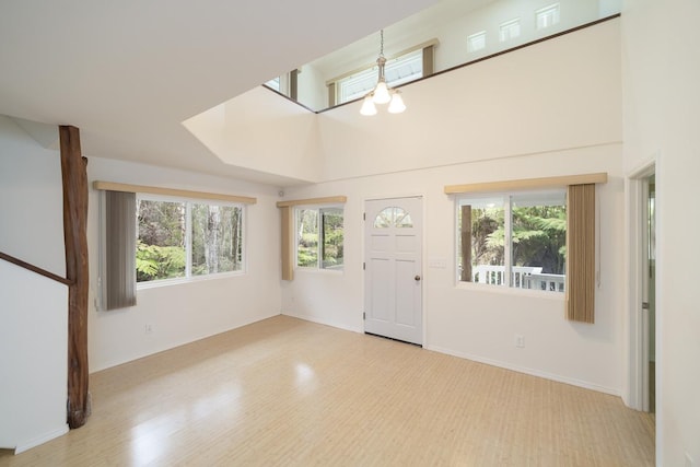 foyer featuring a towering ceiling, a chandelier, and light hardwood / wood-style floors