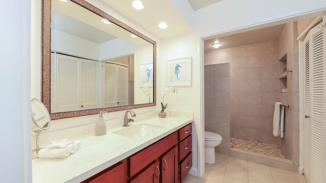 bathroom with tile patterned floors, vanity, tiled shower, and toilet