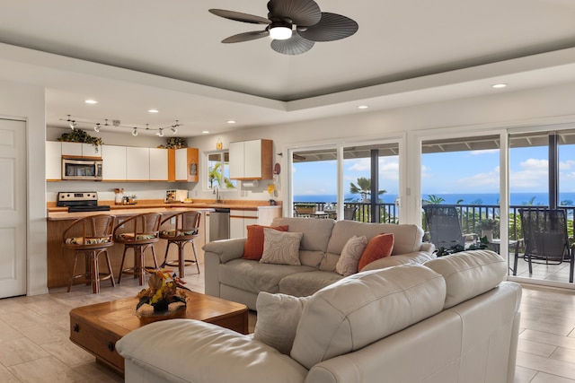 living room featuring ceiling fan, light hardwood / wood-style flooring, and a water view