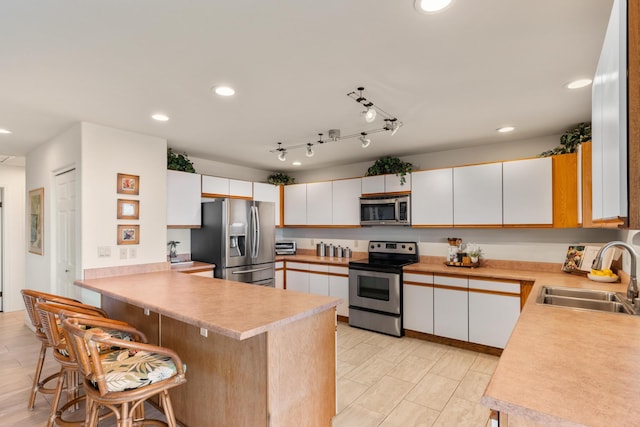 kitchen with white cabinets, stainless steel appliances, kitchen peninsula, and sink