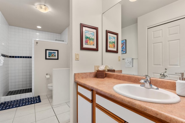 bathroom featuring tiled shower, tile patterned flooring, vanity, and toilet