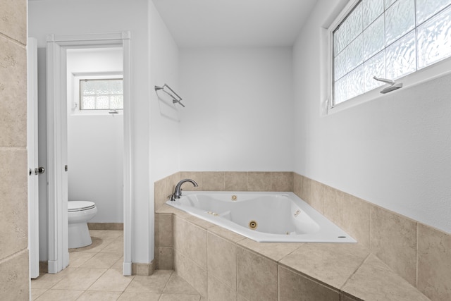 bathroom featuring a relaxing tiled tub, tile patterned flooring, and toilet