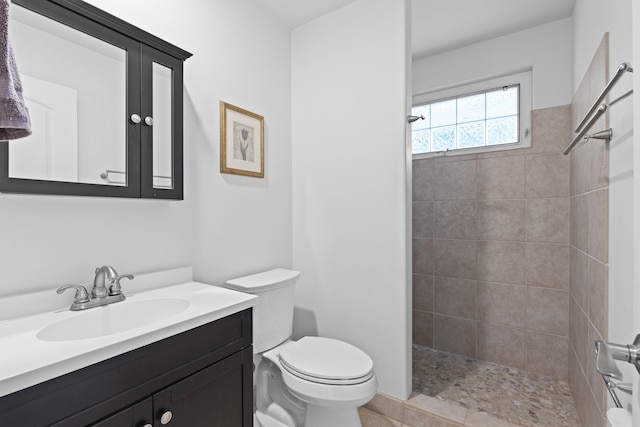 bathroom featuring vanity, toilet, and a tile shower