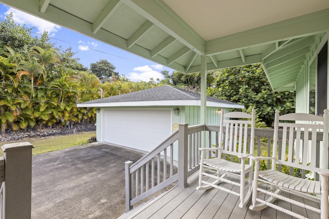 wooden terrace featuring a garage and an outbuilding