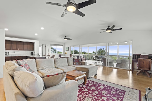 living room with vaulted ceiling, light hardwood / wood-style floors, and ceiling fan