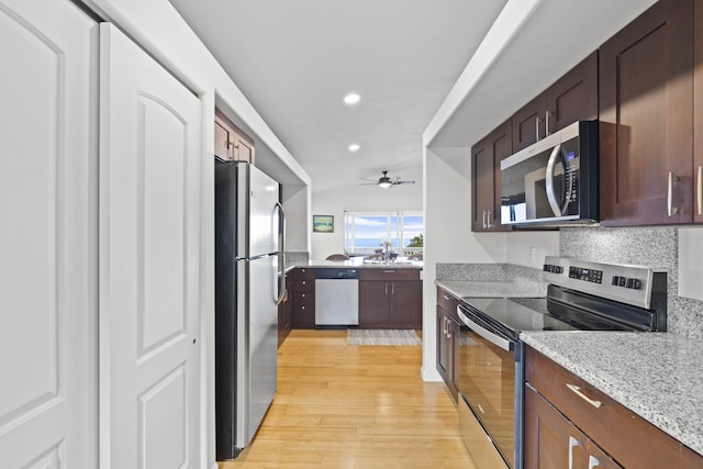 kitchen with lofted ceiling, light hardwood / wood-style flooring, stainless steel appliances, light stone countertops, and decorative backsplash