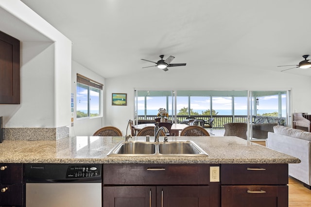 kitchen featuring lofted ceiling, sink, stainless steel dishwasher, and light stone counters