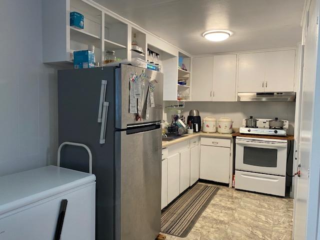 kitchen with white cabinets, white electric range, and stainless steel refrigerator