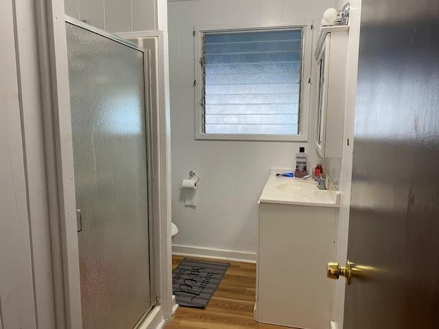 bathroom featuring vanity, toilet, wood-type flooring, and walk in shower