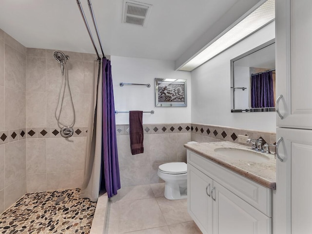 bathroom featuring tile patterned floors, vanity, tile walls, and walk in shower