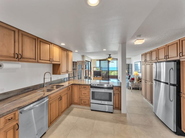 kitchen with kitchen peninsula, appliances with stainless steel finishes, ceiling fan, sink, and light tile patterned flooring