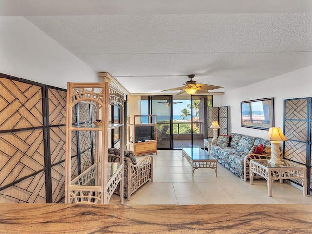 tiled living room featuring a textured ceiling, expansive windows, and ceiling fan