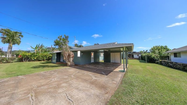 back of property with a carport and a lawn