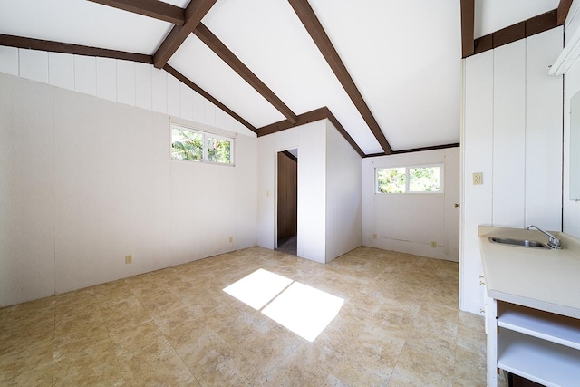 unfurnished living room featuring lofted ceiling with beams, sink, and a healthy amount of sunlight