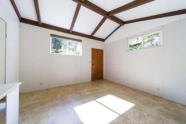 spare room with lofted ceiling with beams and a wealth of natural light