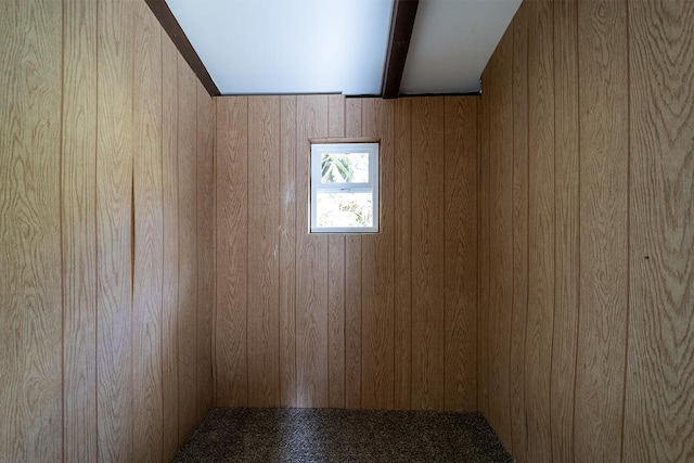 empty room with beam ceiling and wooden walls