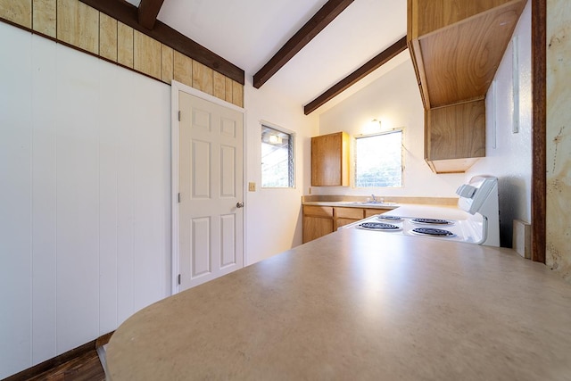 kitchen with sink, lofted ceiling with beams, and range