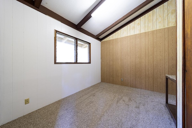 carpeted spare room featuring lofted ceiling with beams and wooden walls