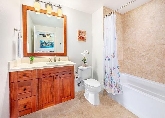 full bathroom featuring vanity, ceiling fan, shower / bathtub combination with curtain, and toilet