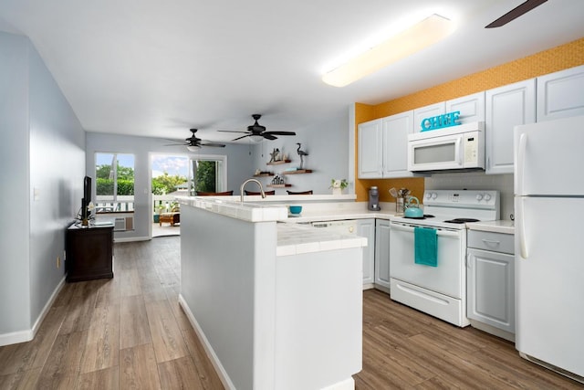 kitchen with kitchen peninsula, white cabinets, light hardwood / wood-style floors, and white appliances