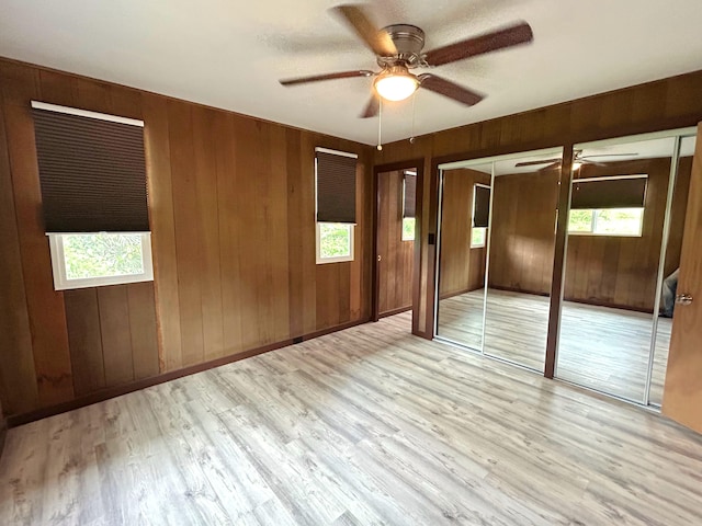 empty room featuring a wealth of natural light, light hardwood / wood-style floors, and wooden walls