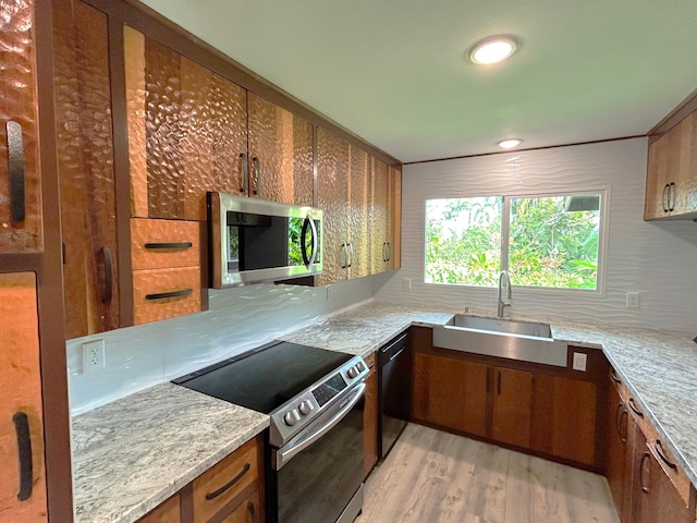 kitchen featuring stainless steel appliances, sink, light stone counters, and light hardwood / wood-style flooring