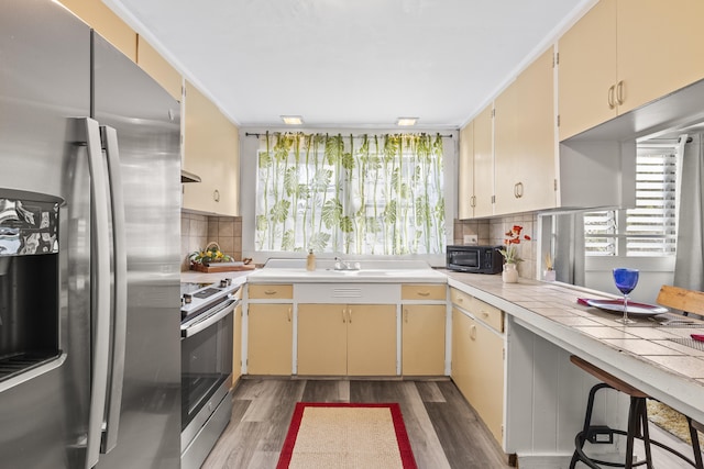 kitchen with cream cabinetry, plenty of natural light, stainless steel appliances, and dark wood-type flooring