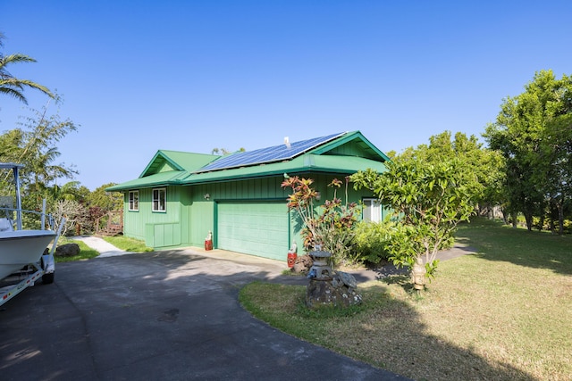 view of front of property featuring a front yard, solar panels, and a garage