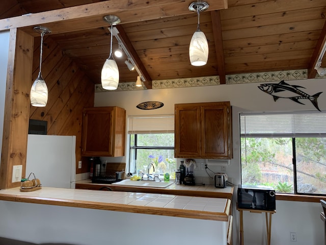 kitchen featuring sink, wooden ceiling, hanging light fixtures, white refrigerator, and tile countertops