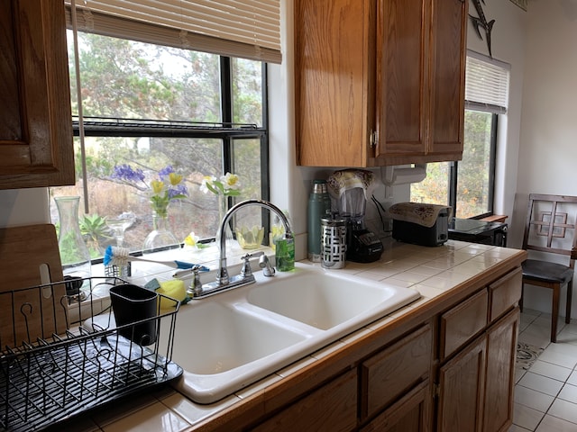 kitchen with tile counters, light tile patterned floors, and sink