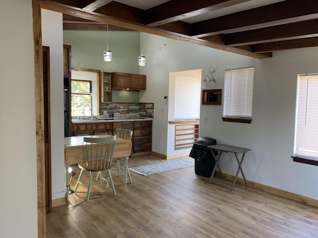 kitchen featuring beamed ceiling, decorative light fixtures, light hardwood / wood-style floors, and sink