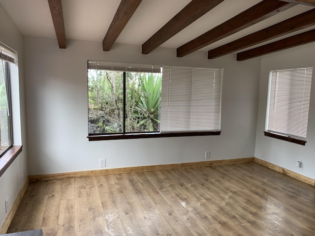 spare room featuring beam ceiling and light hardwood / wood-style flooring