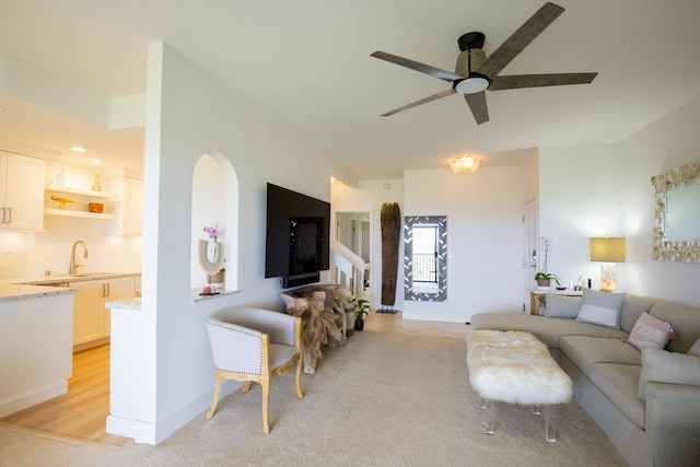 carpeted living room with ceiling fan and sink