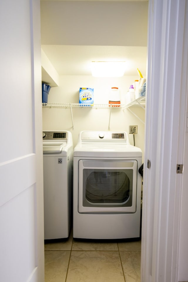 clothes washing area with washing machine and dryer and light tile patterned floors