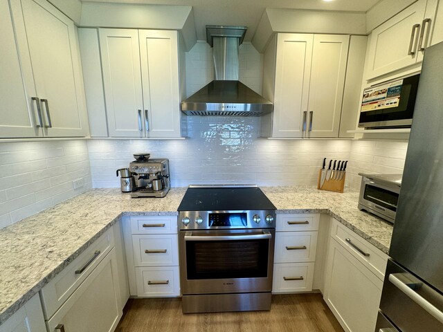 kitchen featuring white cabinets, decorative backsplash, wall chimney exhaust hood, and stainless steel appliances