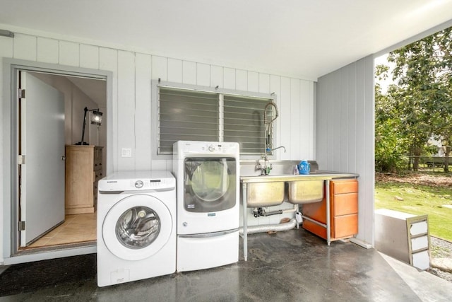 clothes washing area featuring separate washer and dryer, sink, and wooden walls