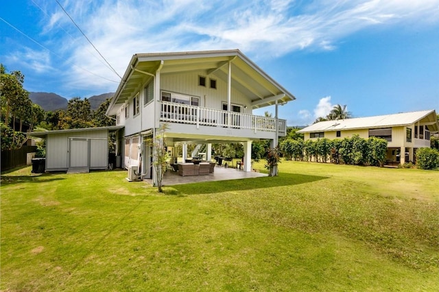 rear view of house featuring an outdoor living space, a storage unit, a patio area, and a lawn