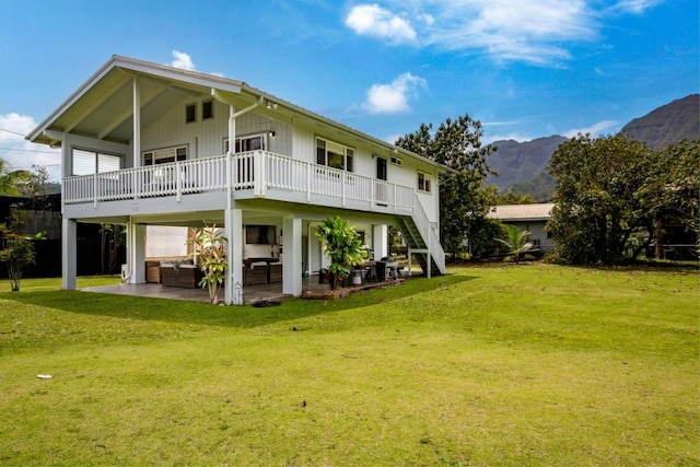 back of property with a lawn, a mountain view, outdoor lounge area, and a patio