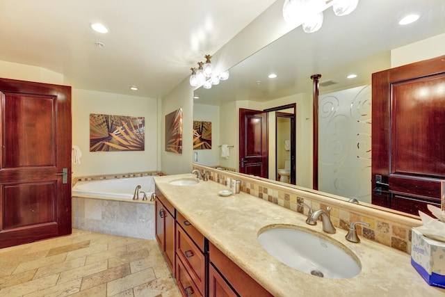 bathroom with vanity, toilet, and tiled bath